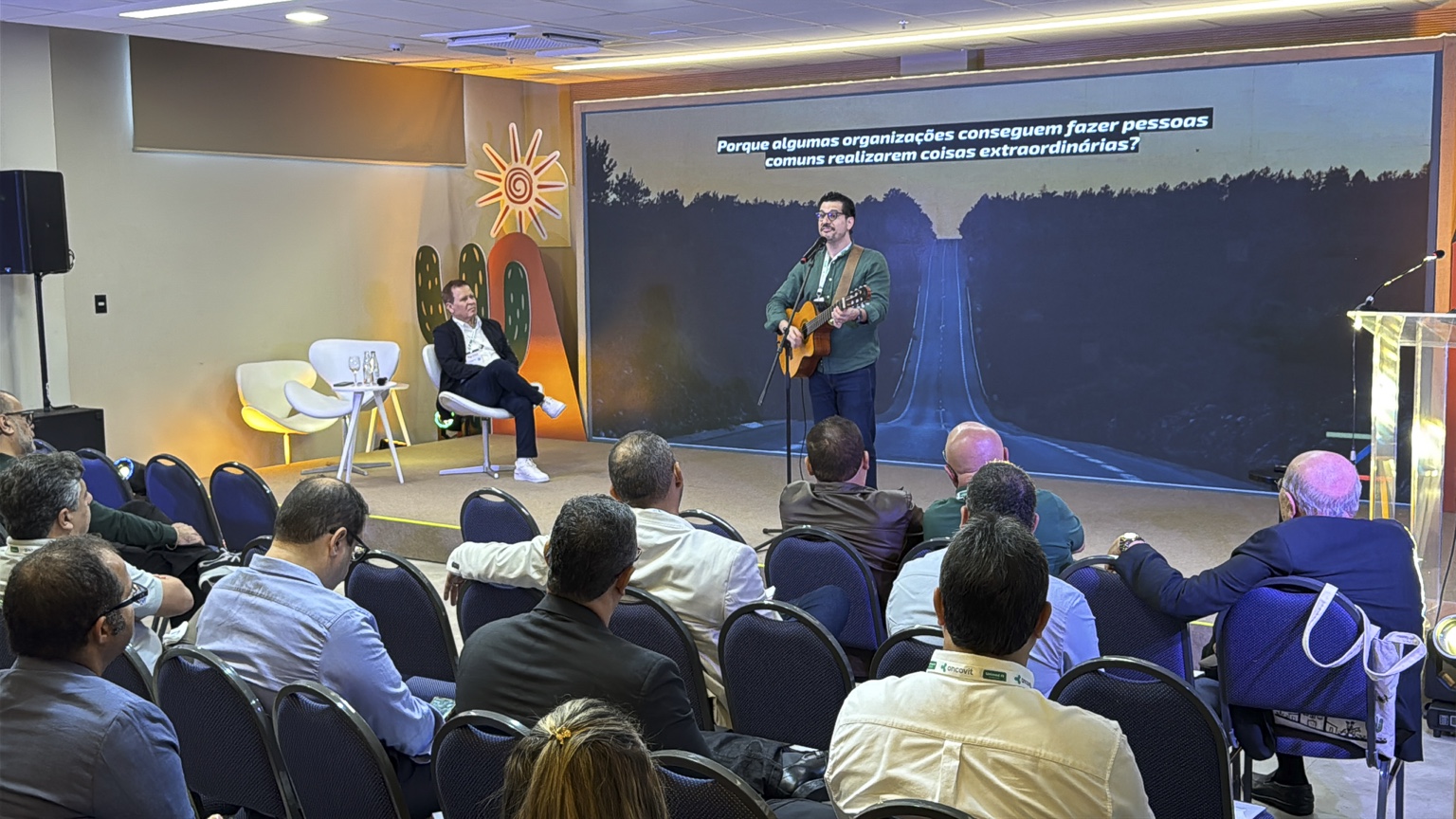 Cleber Zequetto toca violão no palco diante do público